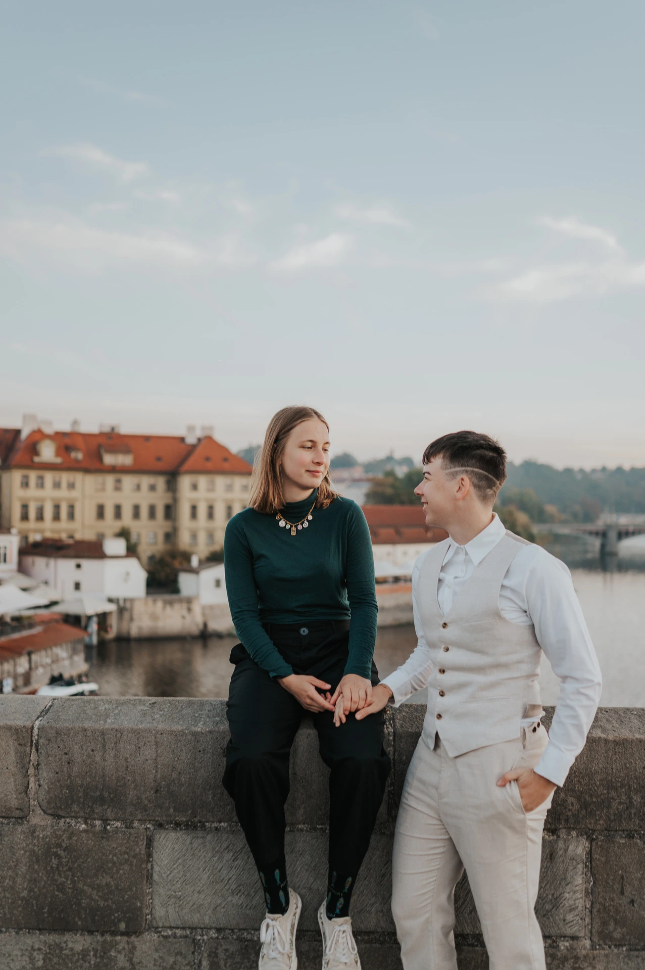 Couple smiling beside the Charles Bridge parapet during a couple photoshoot in Prague.