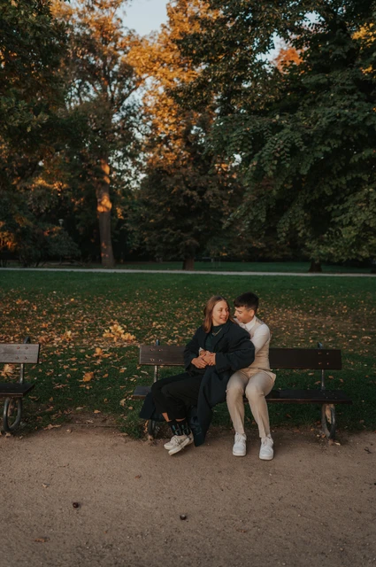 Prague couple photoshoot: wide portrait of the couple on a bench in Kampa. Wide portrait of the couple on a bench in Kampa during a couple photoshoot in Prague.