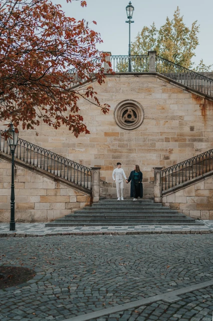 Prague couple photoshoot: wide portrait of the couple on the Kampa stone stairs. Wide portrait of the couple on the Kampa stone stairs during a couple photoshoot in Prague.