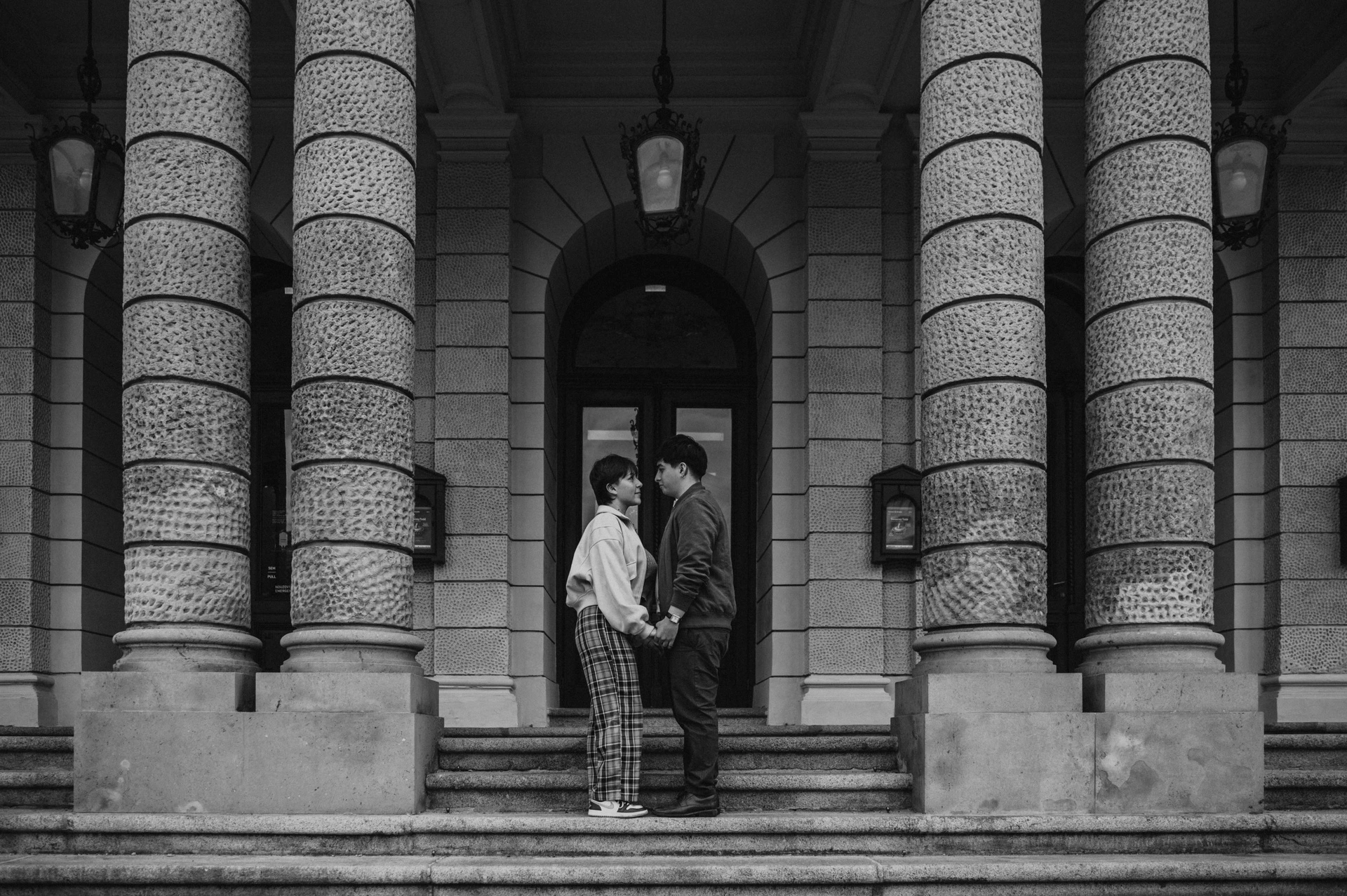 Black and white portrait beneath the opera colonnade during a couple photoshoot in Prague.