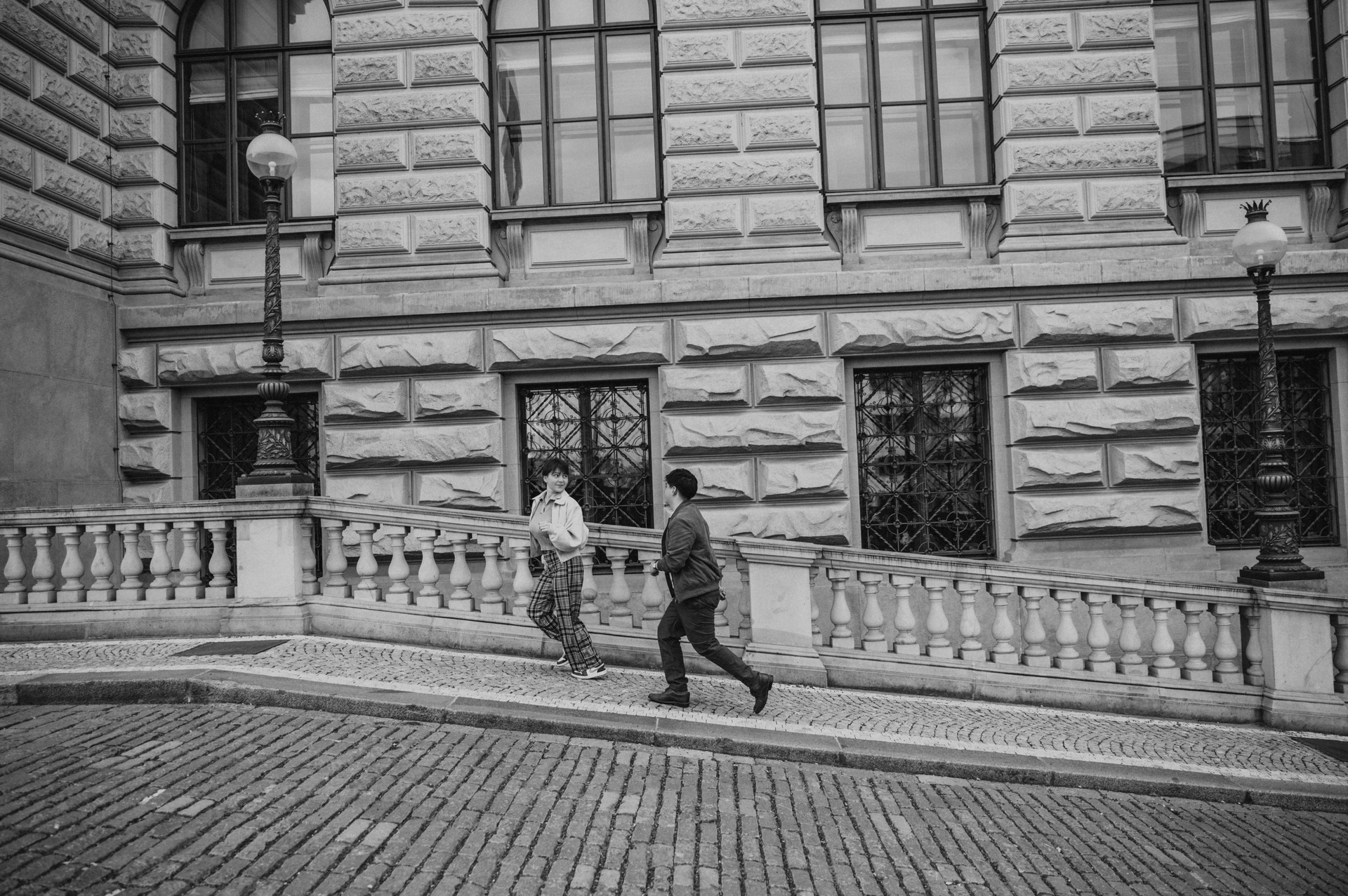 Black and white walk beside the museum windows during a couple photoshoot in Prague.