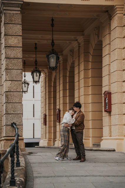 Couple embracing beneath the opera arcade during a couple photoshoot in Prague.