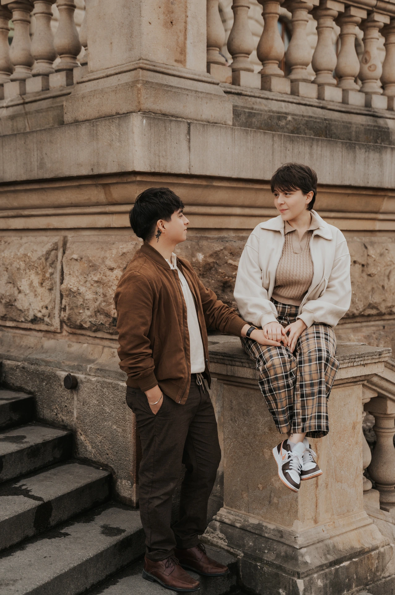Couple exchanging smiles beside the museum steps during a couple photoshoot in Prague.
