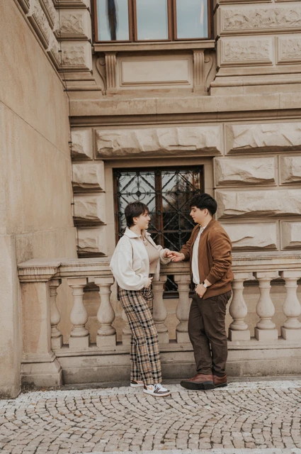 Prague couple photoshoot: couple facing each other beside a carved museum window. Couple facing each other beside a carved museum window during a couple photoshoot in Prague.