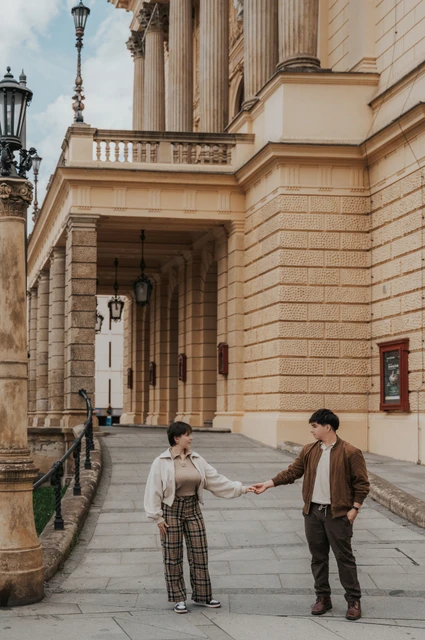 Prague couple photoshoot: couple holding hands beside the opera colonnade. Couple holding hands beside the opera colonnade during a couple photoshoot in Prague.