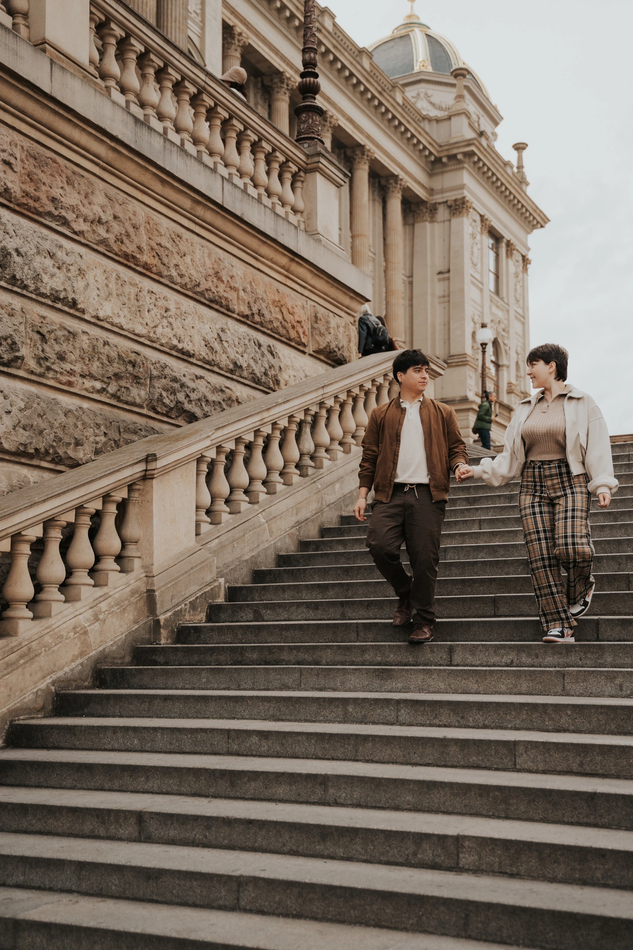 Couple holding hands on the broad museum staircase during a couple photoshoot in Prague.