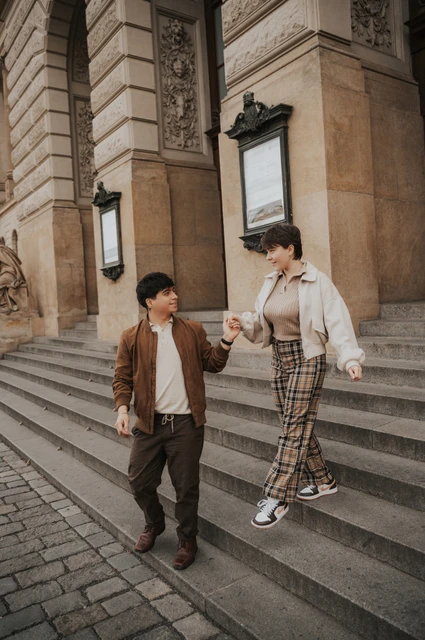 Prague couple photoshoot: couple holding hands while walking down the steps. Couple holding hands while walking down the steps during a couple photoshoot in Prague.