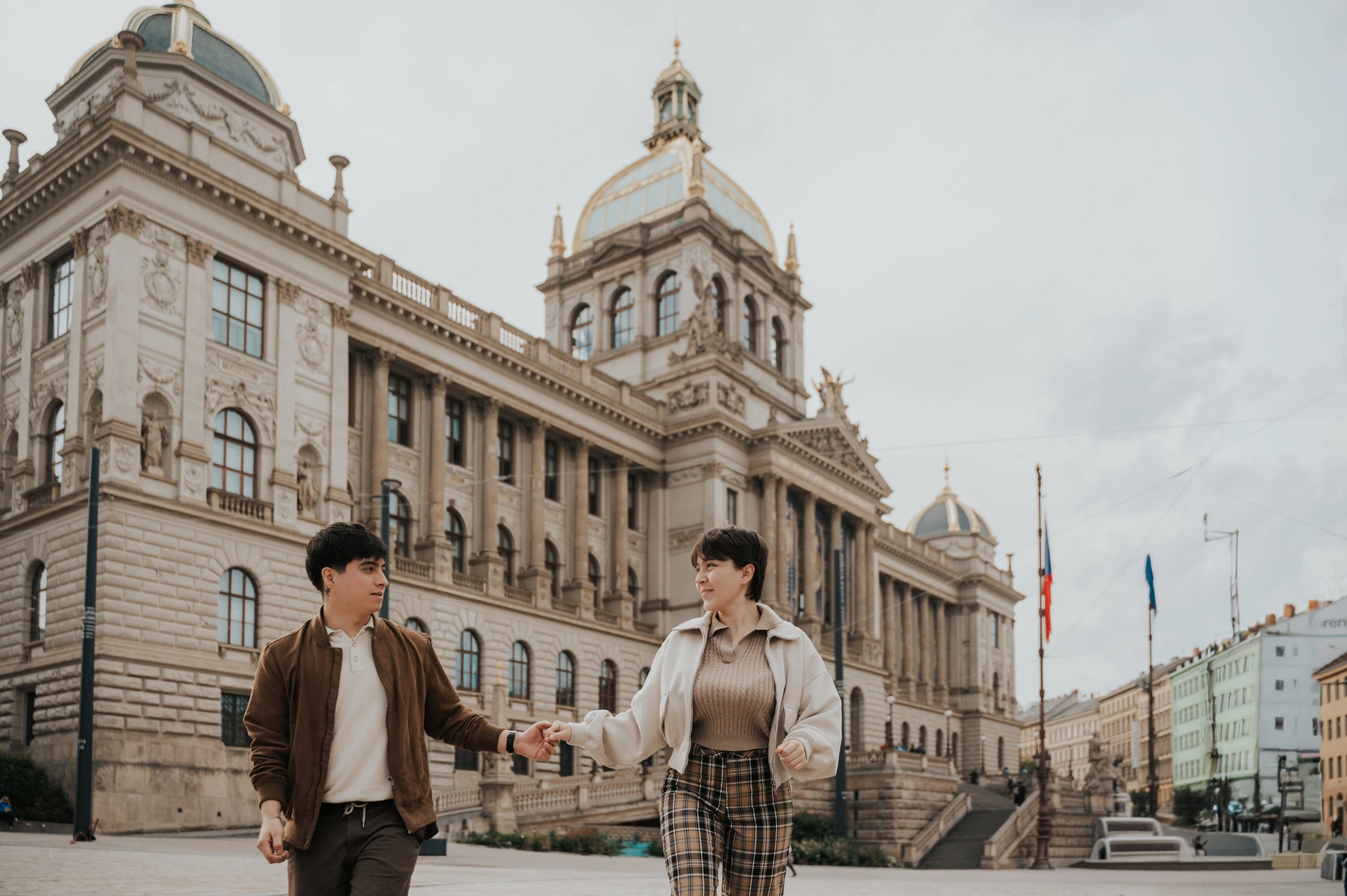 Prague couple photoshoot: couple holding hands with the National Museum in the background. Couple holding hands with the National Museum in the background during a couple photoshoot in Prague.