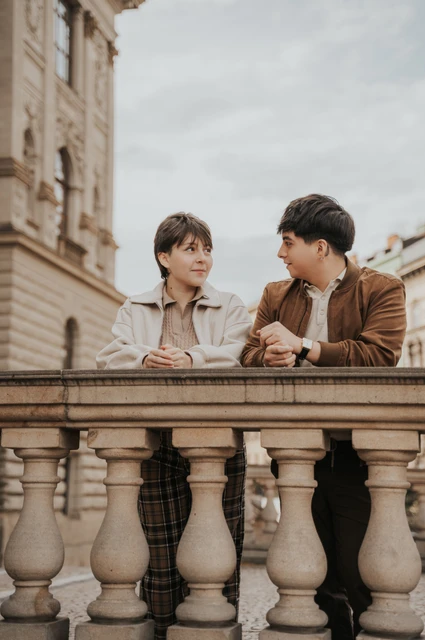 Prague couple photoshoot: couple leaning together over a stone railing. Couple leaning together over a stone railing during a couple photoshoot in Prague.