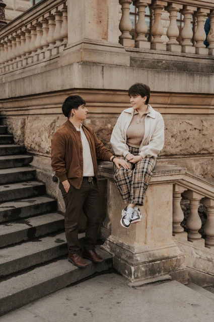 Couple pausing by a carved stone balustrade during a couple photoshoot in Prague.