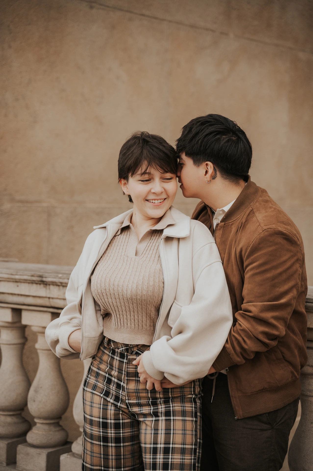 Couple sharing a kiss beside the stone railing during a couple photoshoot in Prague.