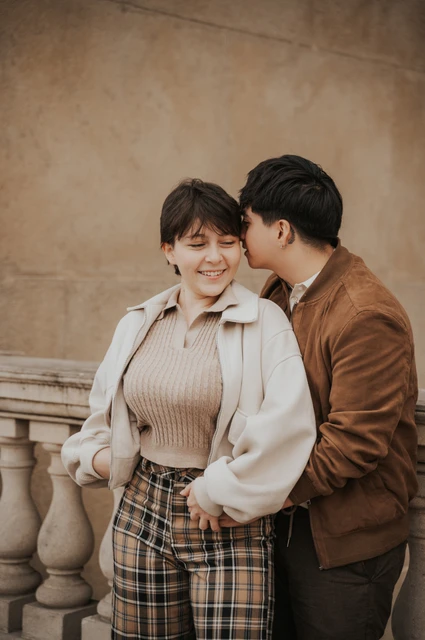 Couple sharing a kiss beside the stone railing during a couple photoshoot in Prague.