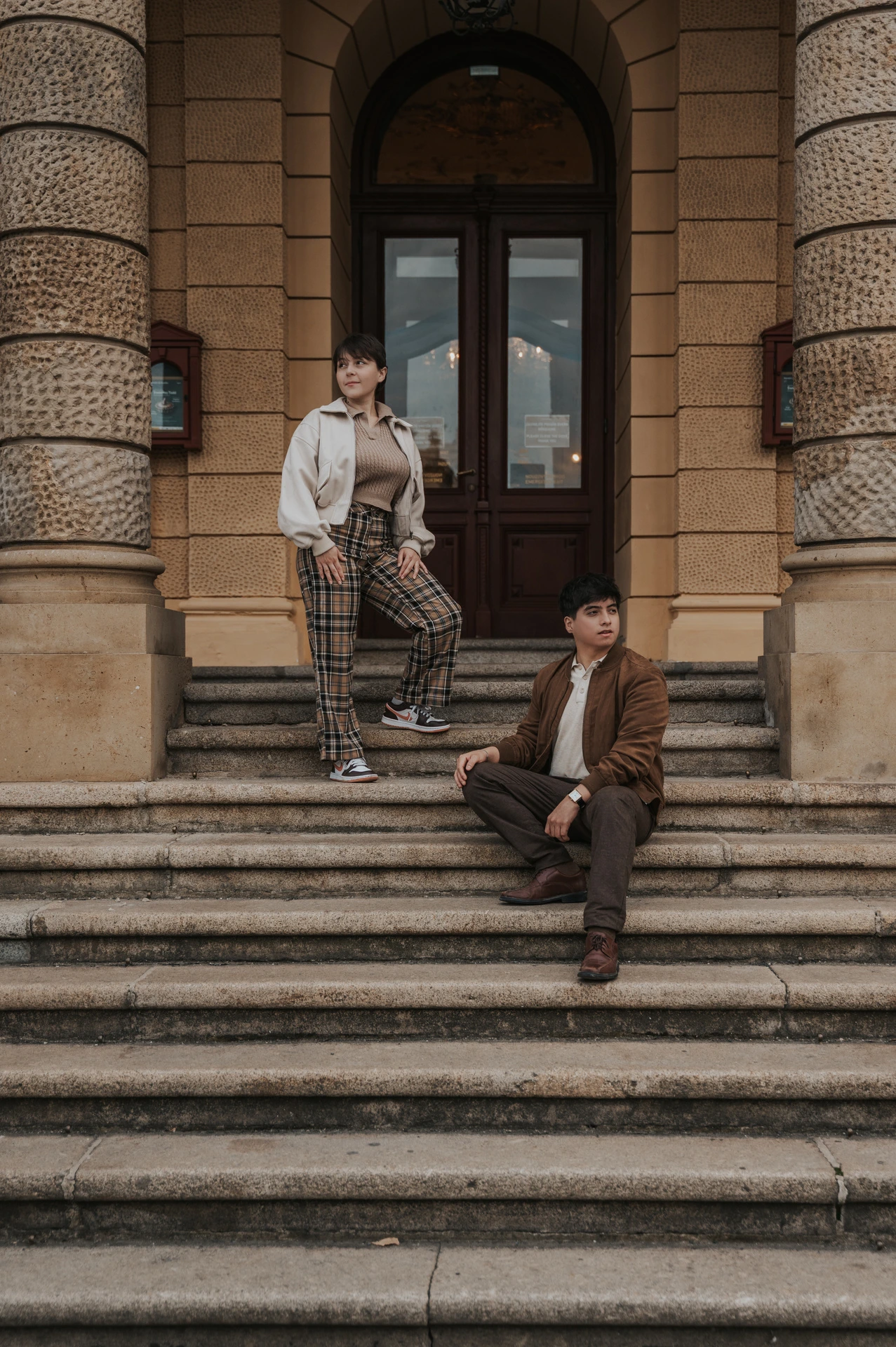 Couple sitting and standing on the opera steps during a couple photoshoot in Prague.