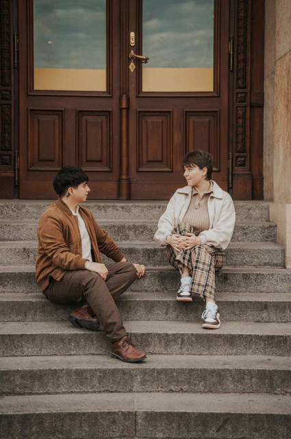 Prague couple photoshoot: couple sitting on the steps beneath wooden doors. Couple sitting on the steps beneath wooden doors during a couple photoshoot in Prague.