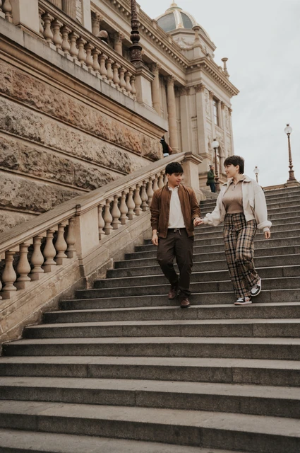 Prague couple photoshoot: couple smiling as they descend the museum staircase. Couple smiling as they descend the museum staircase during a couple photoshoot in Prague.