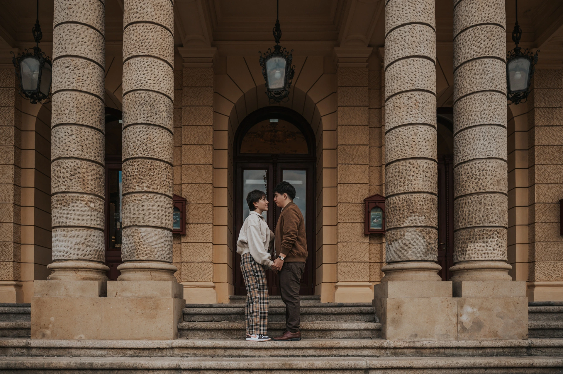 Couple smiling together between the opera columns during a couple photoshoot in Prague.