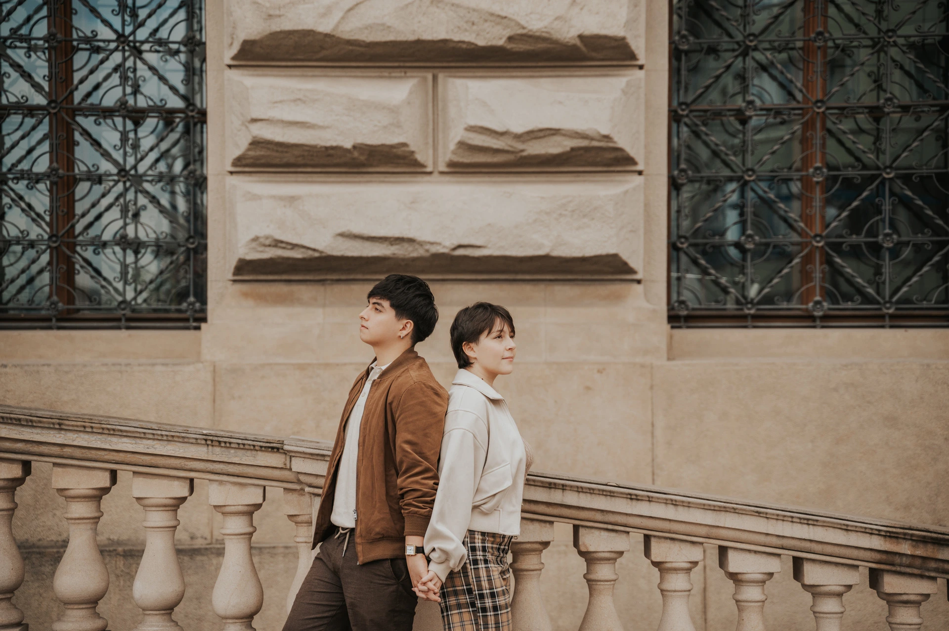 Couple standing back to back beside a museum window during a couple photoshoot in Prague.
