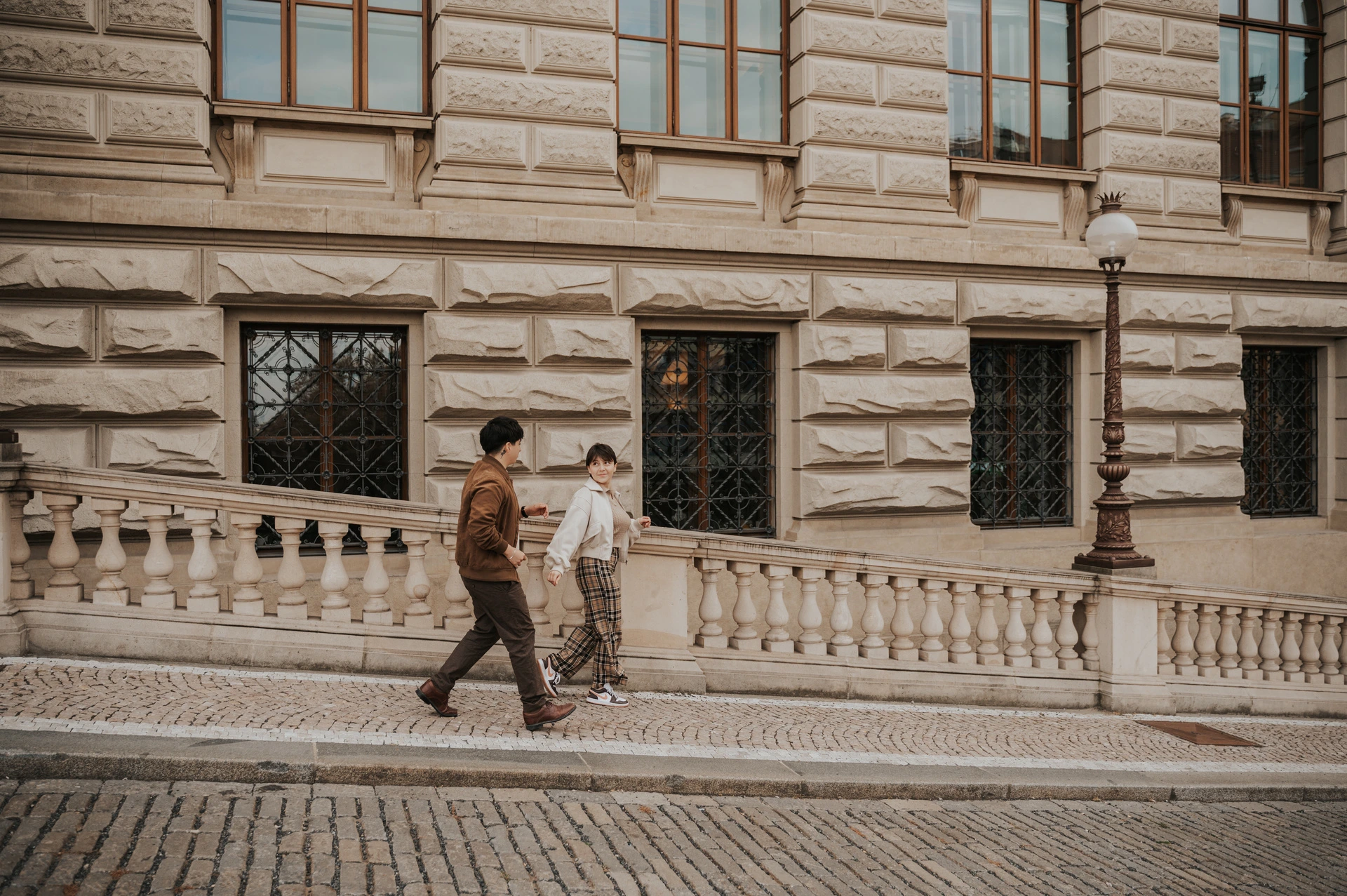 Couple walking along the patterned pavement by the museum during a couple photoshoot in Prague.