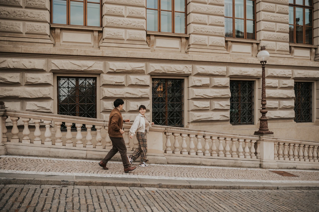 Prague couple photoshoot: couple walking along the patterned pavement by the museum. Couple walking along the patterned pavement by the museum during a couple photoshoot in Prague.