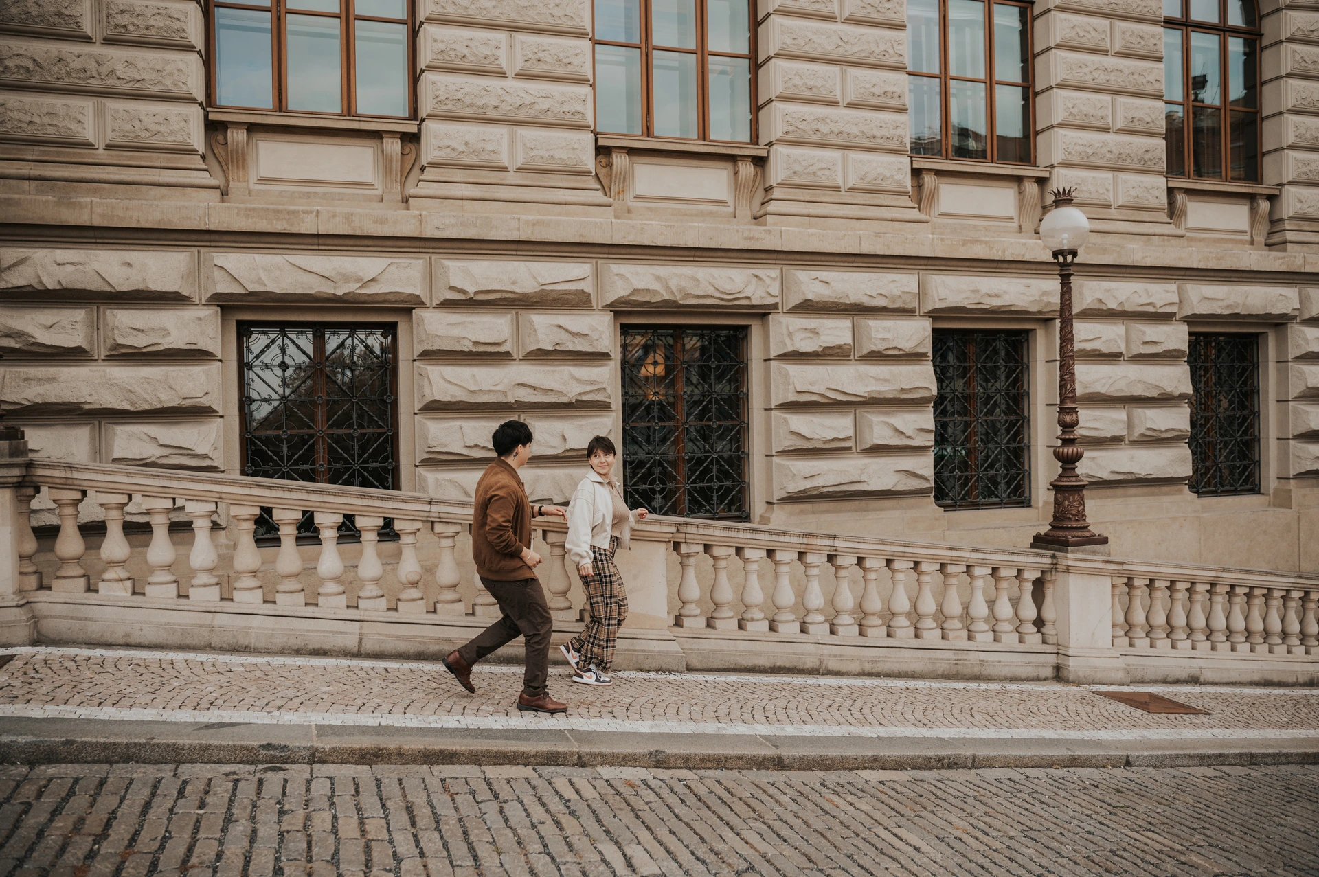 Wide portrait of the couple beside the museum facade during a couple photoshoot in Prague.