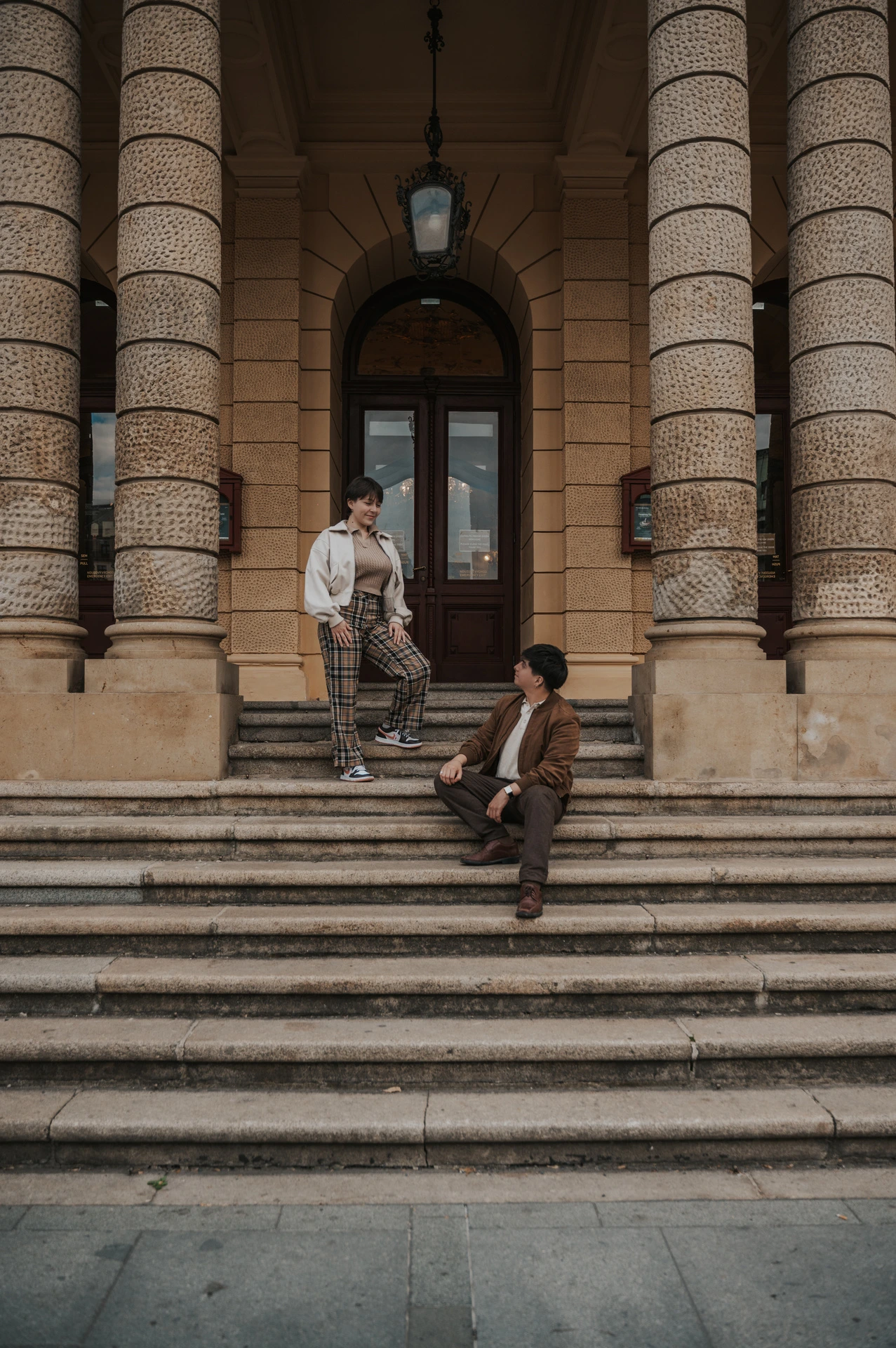 Wide portrait of the couple on the columned entrance steps during a couple photoshoot in Prague.
