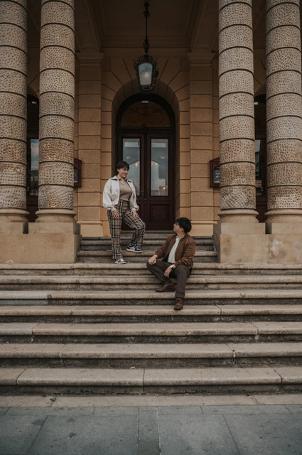 Prague couple photoshoot: wide portrait of the couple on the columned entrance steps. Wide portrait of the couple on the columned entrance steps during a couple photoshoot in Prague.
