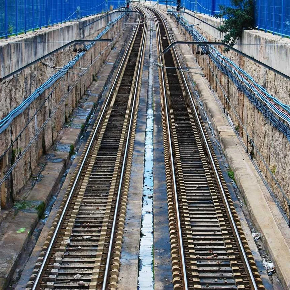 Parallel railway train tracks with perspective leading into distance in urban setting