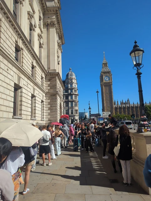 Busy Westminster pavement with people beside a red telephone box and Elizabeth Tower in the background