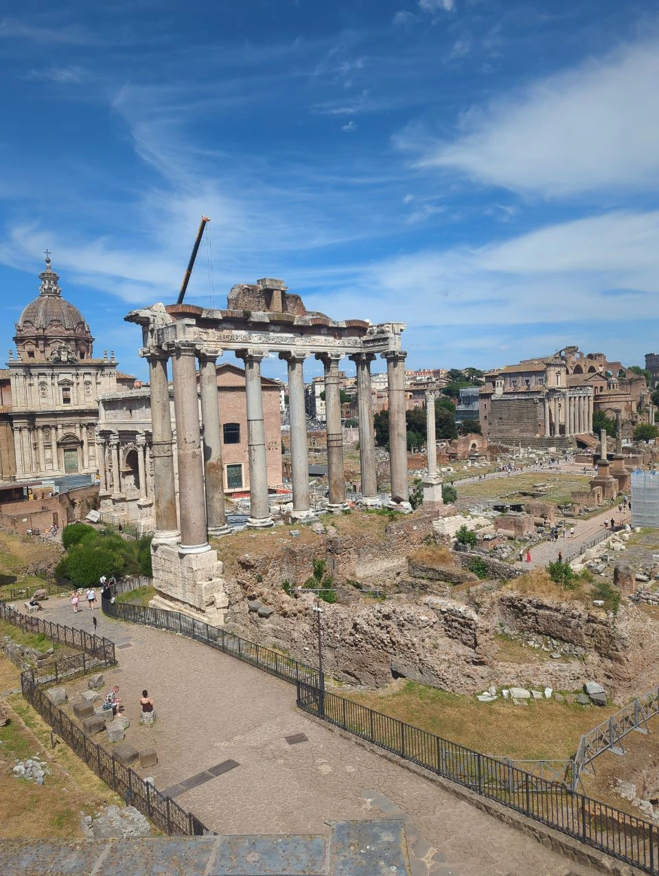 The Roman Forum’s columns, ruins and domed buildings form a layered Rome photoshoot backdrop beneath a bright blue sky.
