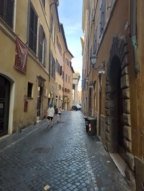 Cobbled Lane near the Pantheon A narrow cobbled lane between yellow and ochre facades leads towards the Pantheon area in Rome.