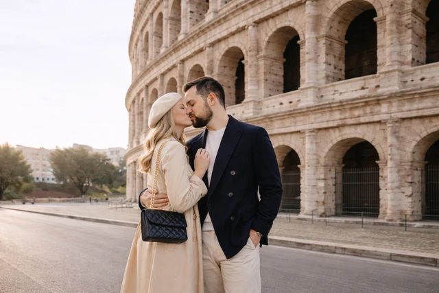 Seance photo couple Rome Un couple qui s'embrasse devant le Colisee a Rome pendant une seance photo couple romantique a l'heure doree.