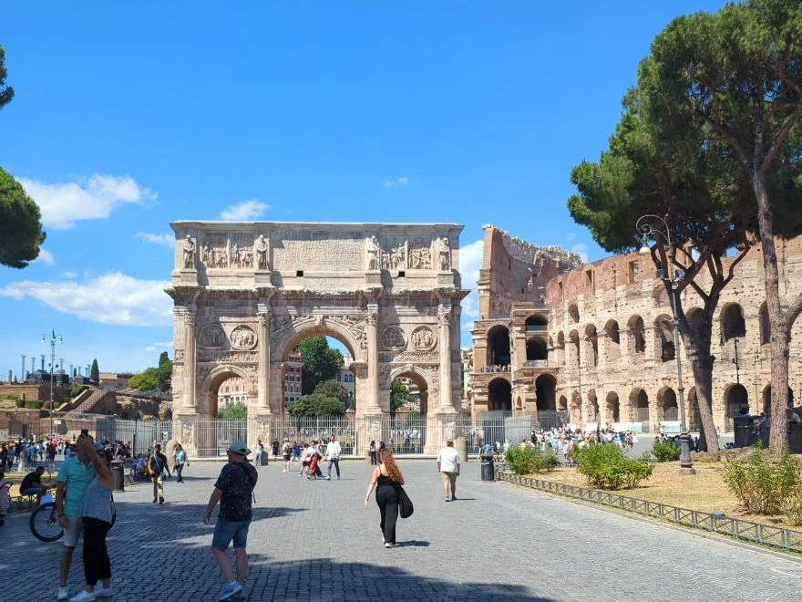 Rome Photoshoot Locations - Ancient Rome The Arch of Constantine stands beside the Colosseum as visitors cross the broad cobbled approach in Rome.