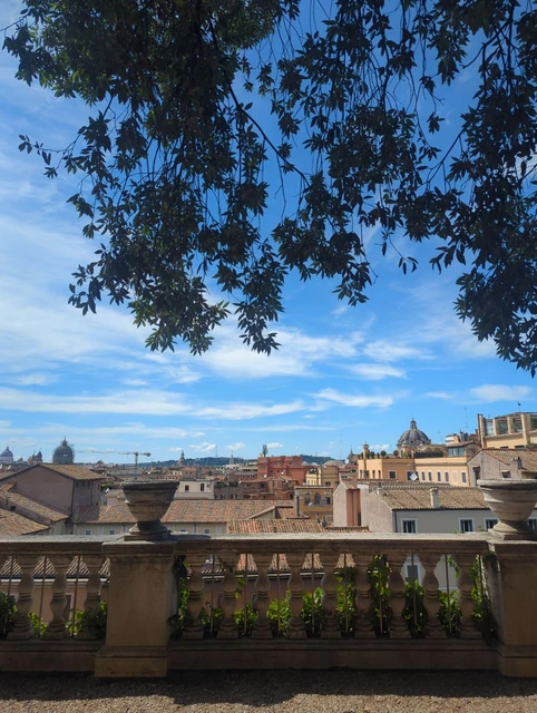 Rome Portrait Guide - Roofscape Terrace A quiet terrace overlooks tiled rooftops and distant domes in Rome, with an open foreground suited to a simple portrait composition.