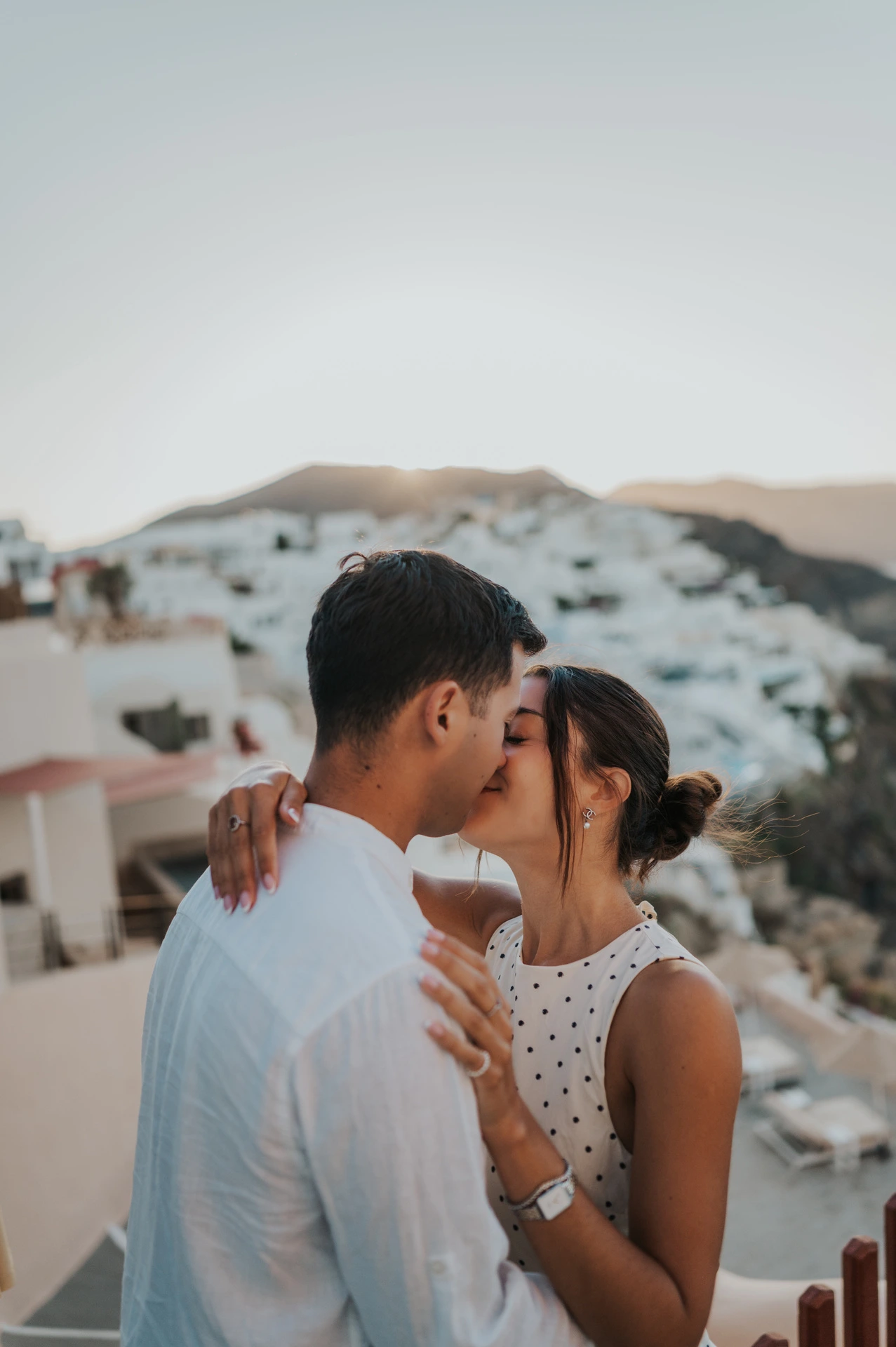 Close portrait of a couple kissing above white hillside houses during their Santorini couple photoshoot.