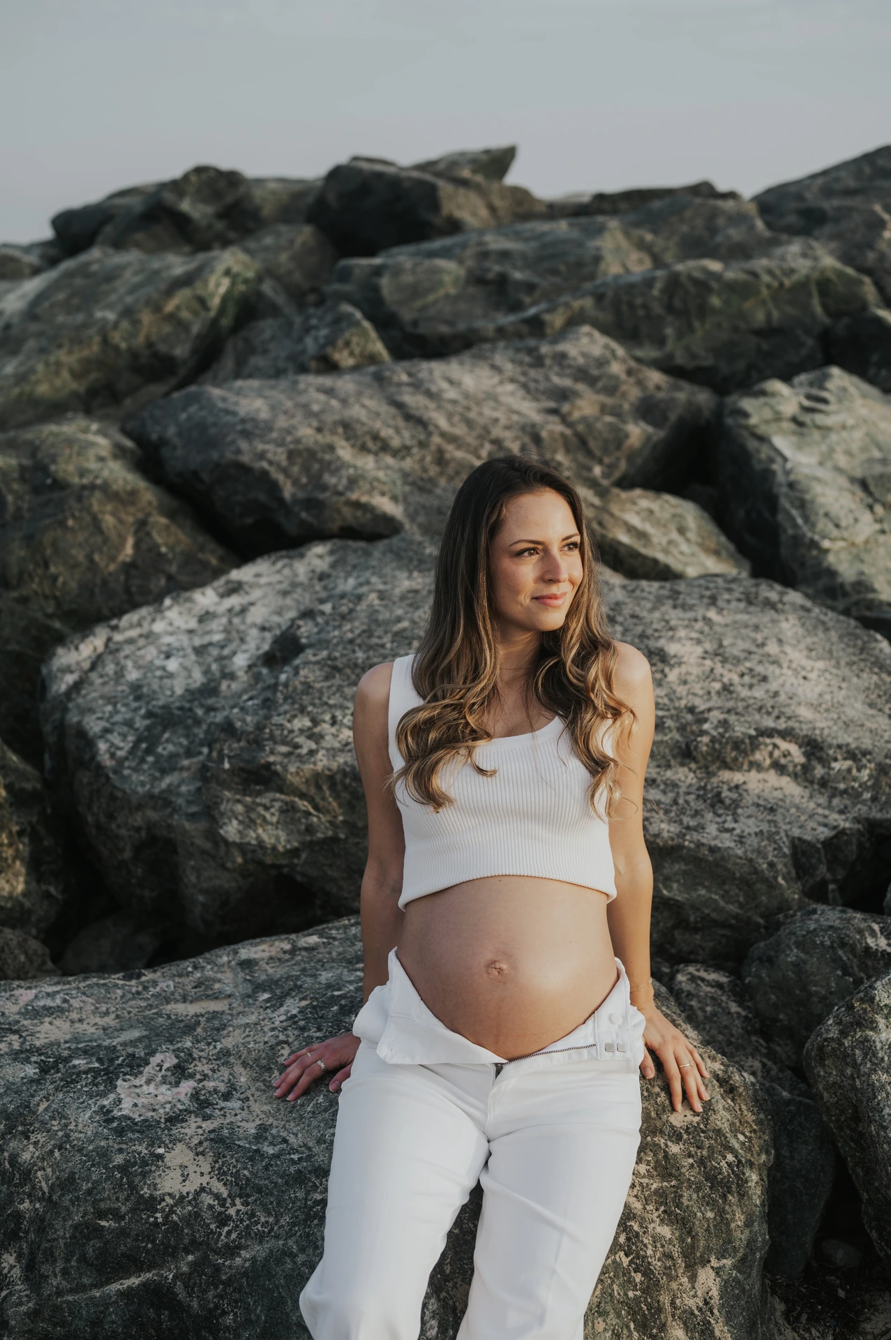 Femme enceinte assise sur les rochers lors d’une séance photo de grossesse à Dubaï.