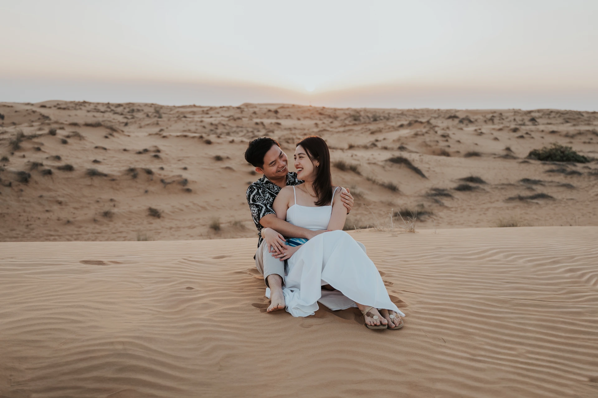 Coppia seduta sulle dune durante un servizio fotografico a Dubai.