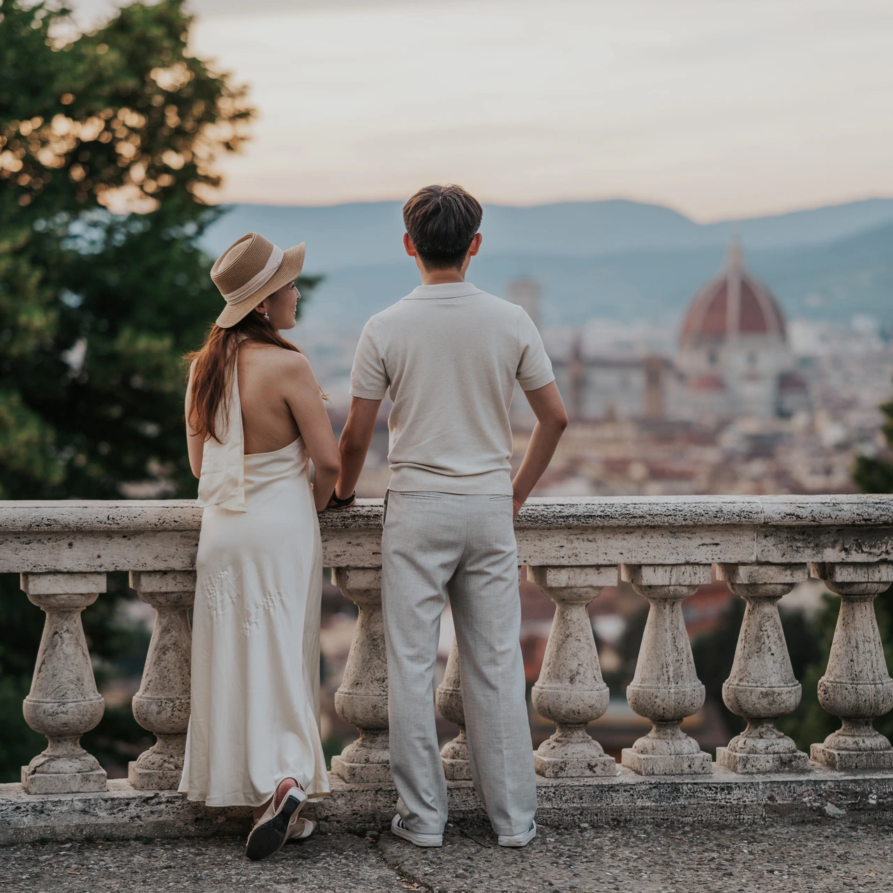 Una pareja fotografiada de espaldas contempla los tejados y el Duomo desde una balaustrada durante una sesión de fotos en Florencia.