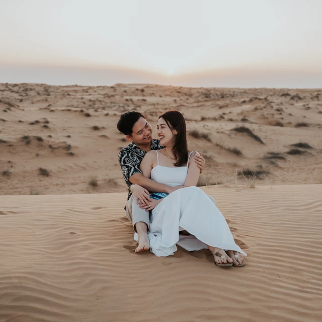 Pareja sentada en las dunas durante una sesión de fotos en Dubái