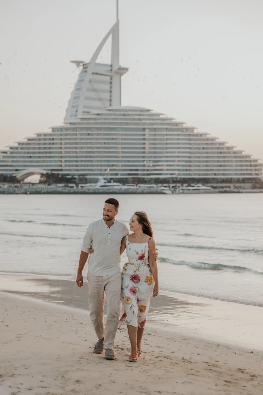 Shoes and accessories for engagement photos Couple walking on beach near Burj Al Arab in engagement outfits