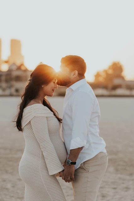 An expecting couple stands close together at golden hour during a Dubai maternity photoshoot, showing a warm outdoor style with soft sunset light.