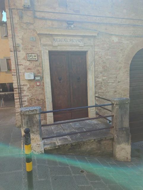 Stone doorway and metal railings on a sloping street in Siena