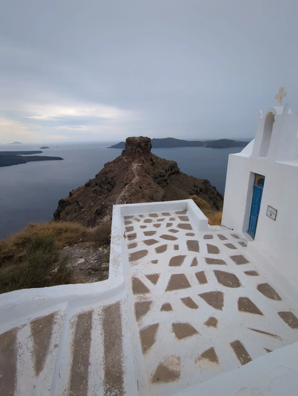 Skaros Rock across the caldera beside a small white Imerovigli church with a blue door