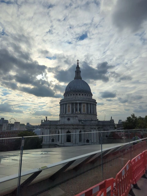 St Paul’s dome viewed from a rooftop behind a glass barrier, with temporary orange barriers in the foreground