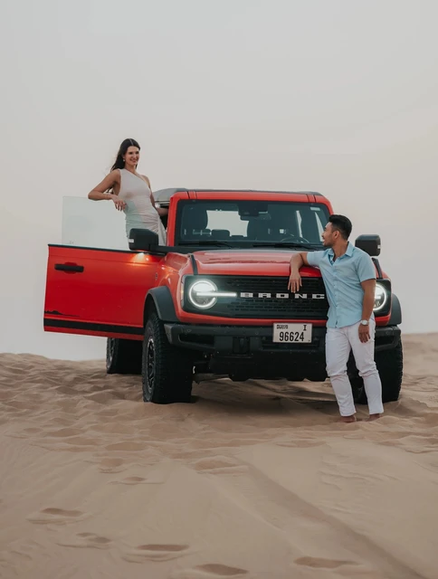 Couple with red jeep in Dubai desert during relaxed shoot day