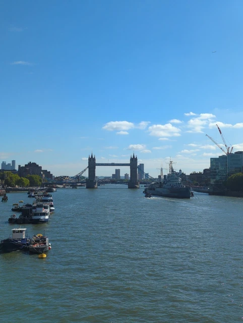 Daytime view east from London Bridge towards Tower Bridge across the Thames, with boats and HMS Belfast