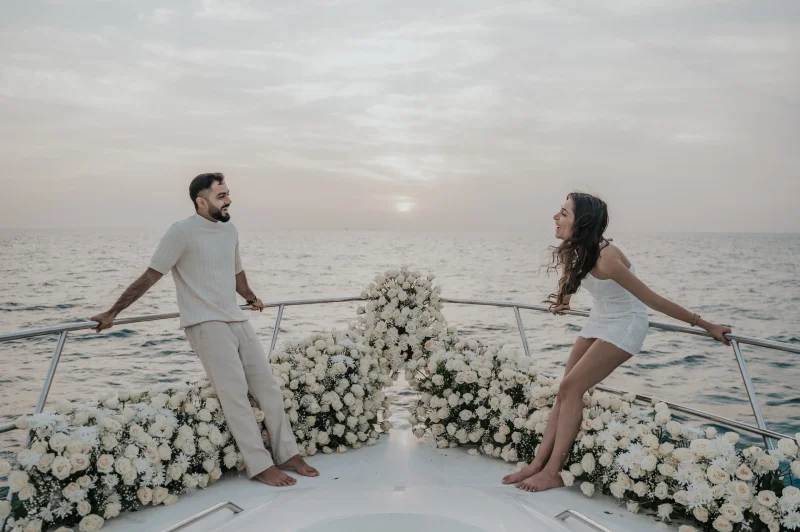 Dubai Proposal Portrait on a Flower-Lined Yacht A couple smiles across a flower-lined yacht bow at sunset during their Dubai proposal photographer portrait session.