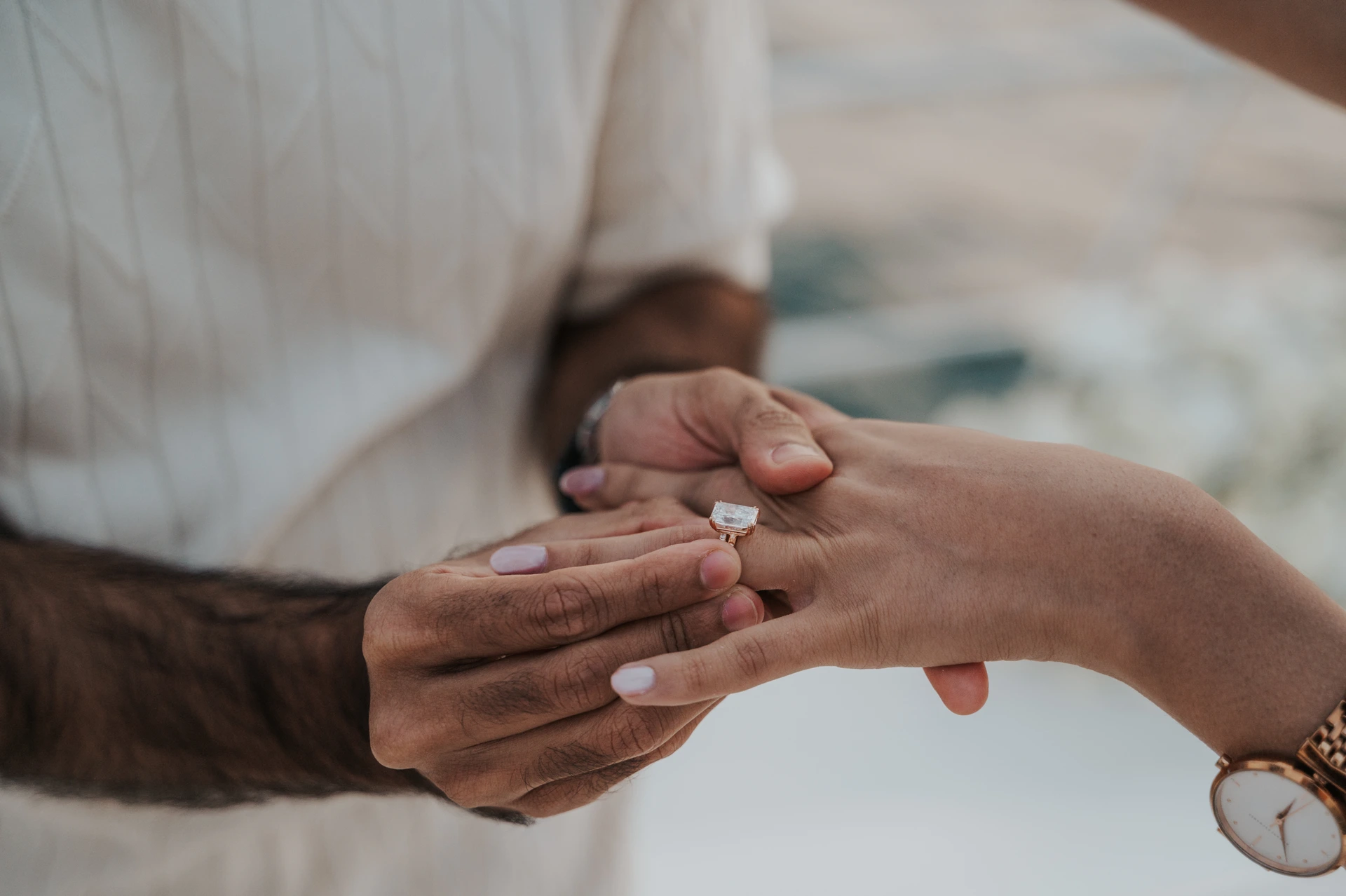 A man slides an engagement ring onto his partner’s finger in a close-up from a Dubai proposal photographer session.