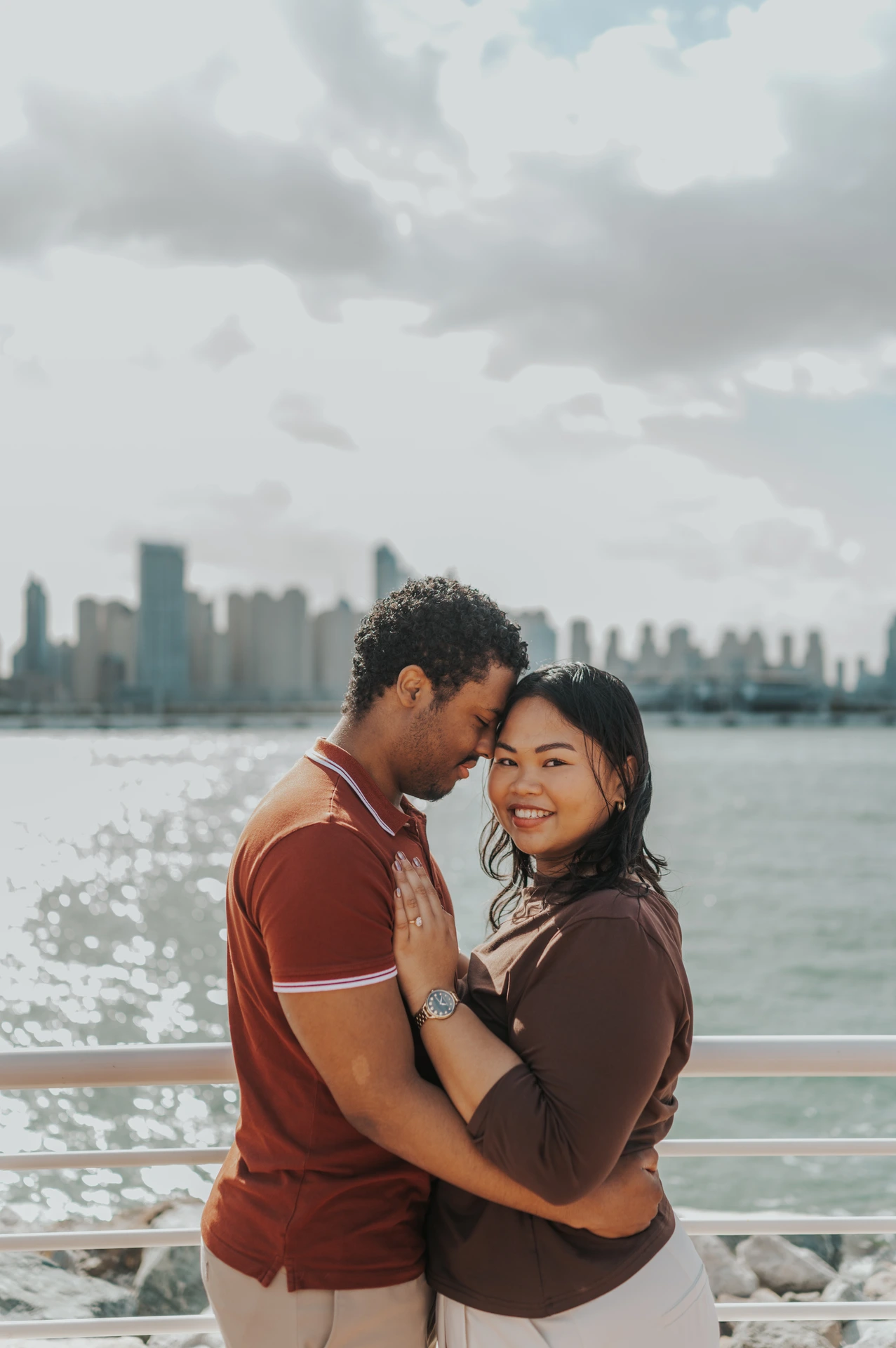 A couple embraces on a yacht deck before the Dubai Marina skyline during a relaxed proposal photography portrait.