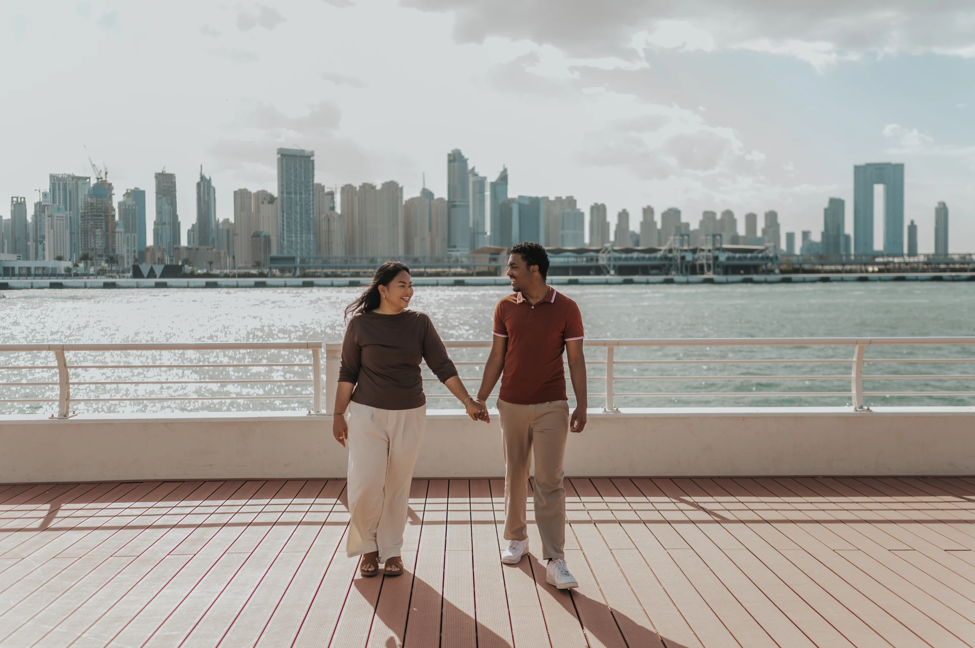 Walking After a Dubai Marina Yacht Proposal A couple walks hand in hand across a yacht deck with the Dubai Marina skyline behind their proposal portrait.