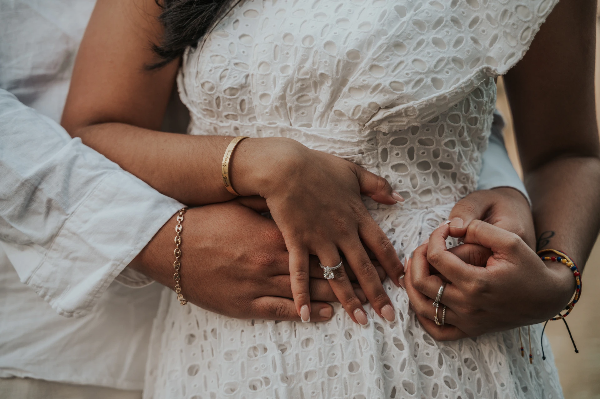 Dubai Proposal Ring Detail During an Embrace A couple embraces while the woman displays her engagement ring against a white dress in a Dubai proposal detail portrait.